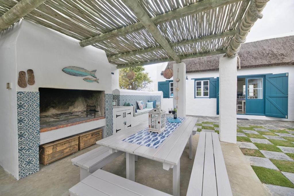 a patio with a table and a fireplace at Zuidste Huisie Fisherman's Cottage in Struisbaai