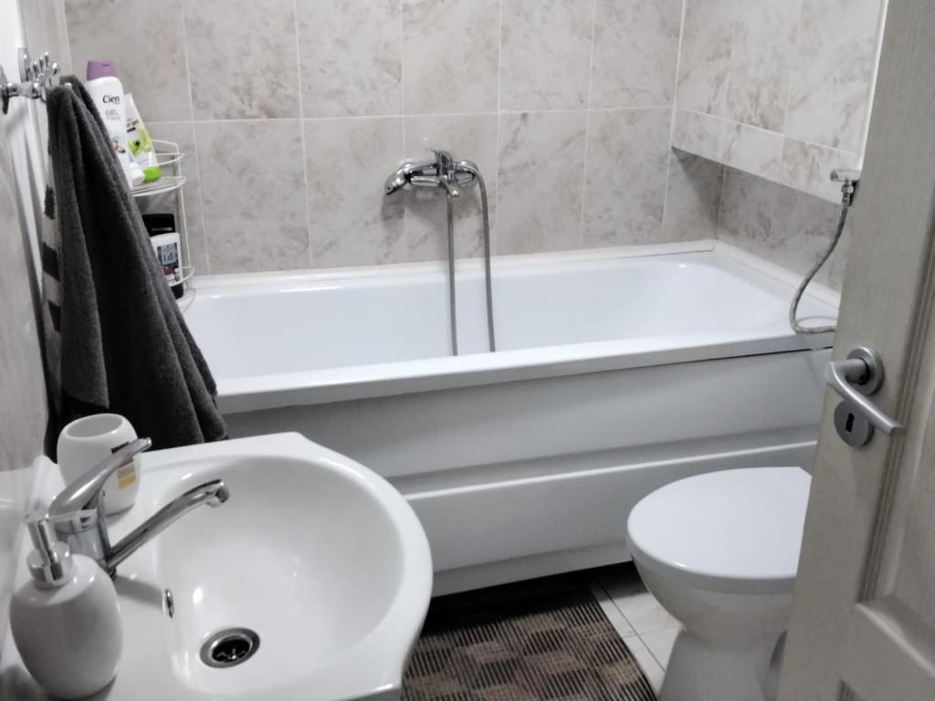 La salle de bains est pourvue d'une baignoire blanche, de toilettes et d'un lavabo. dans l'établissement camera cu baie, à Timişoara