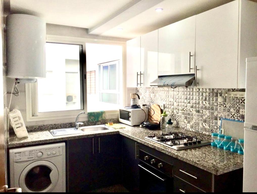 a kitchen with a sink and a washing machine at Tanagra Mall appartement de Luxe a côté de la Gare TGV in Kenitra