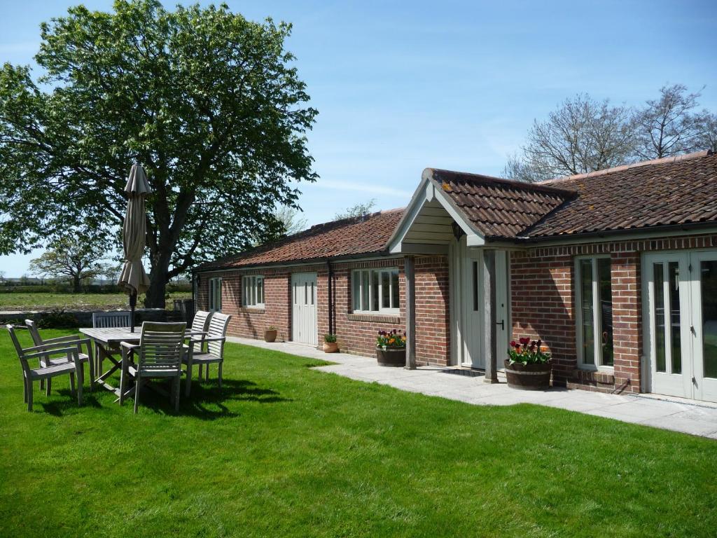 a house with a table and chairs in the yard at The Long Barn in Baltonsborough
