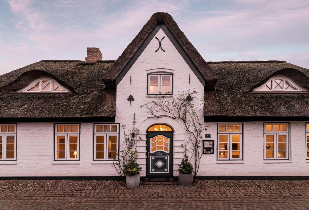 a white house with a thatched roof at von-Deska-Countryhouses-Reeder-Fluegel in Nieblum
