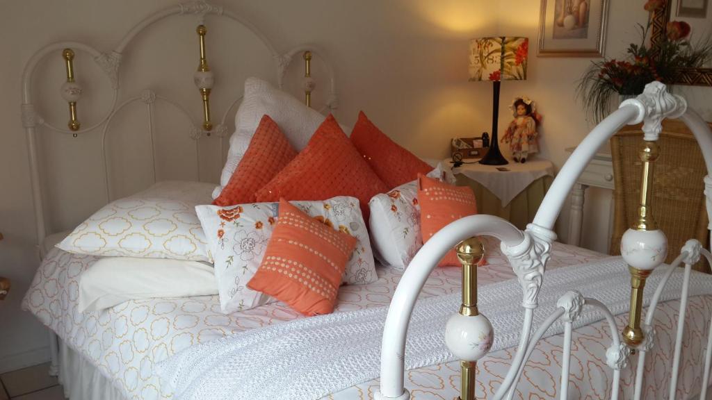 a white bed with orange and white pillows at Harmony Guesthouse in Nelspruit