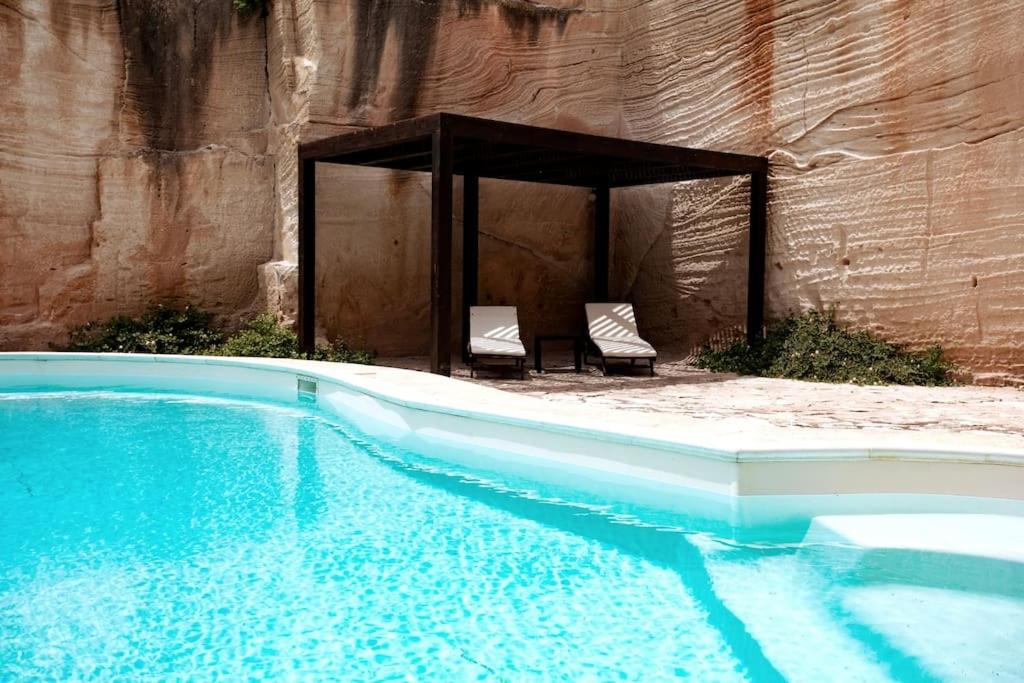 a swimming pool with two chairs next to a wall at Esperanto Suite&Pool - Nuova Gestione 2026 in Favignana