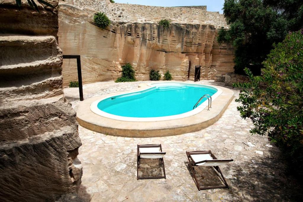 une grande piscine avec deux chaises et une table dans l'établissement Esperanto Suite&Pool, à Favignana