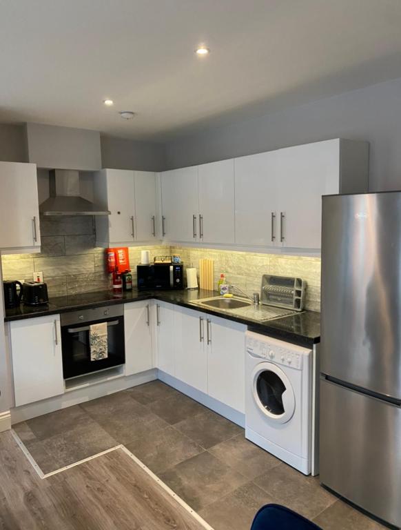 a kitchen with white cabinets and a stainless steel refrigerator at Modern and spacious city centre apartment in Dublin