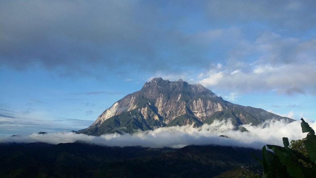a mountain with clouds in front of it at MAK Homstay Downstairs in Kundasang