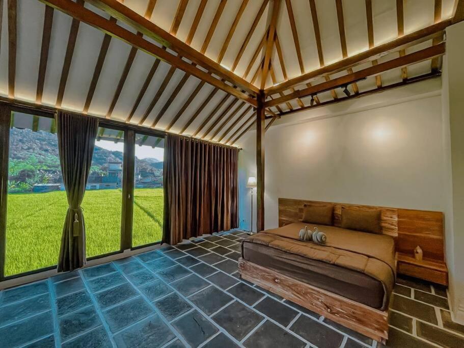 1 dormitorio con 1 cama en una habitación con ventanas grandes en Villa Kamar Tamu Piyungan en Bantul