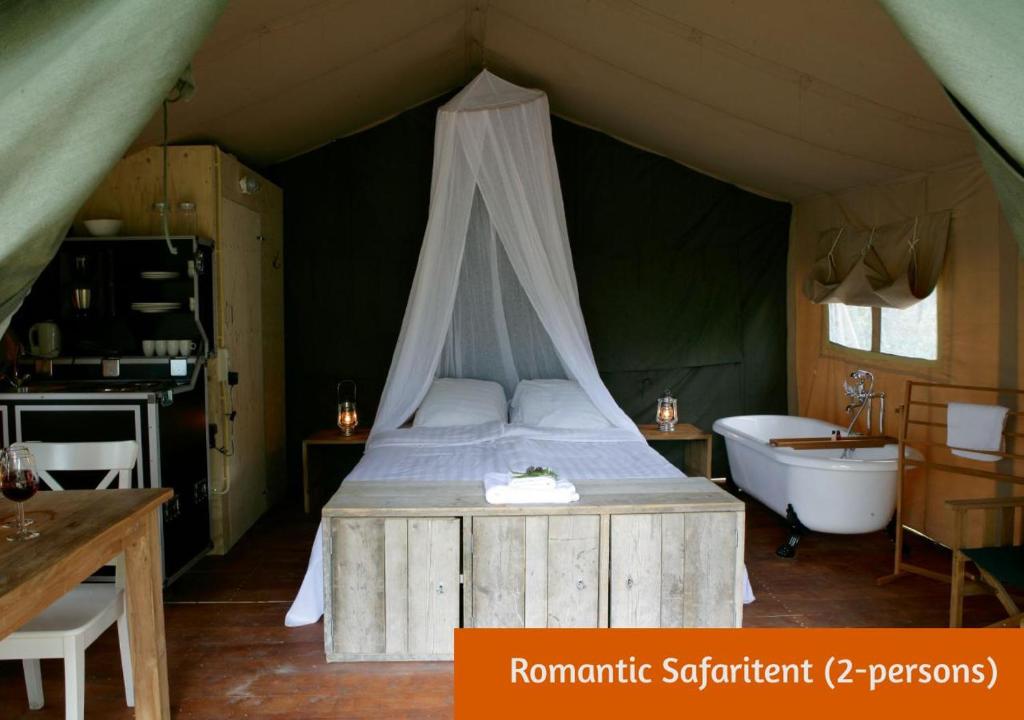 1 dormitorio con cama y bañera en una tienda en Safaritents & Glamping by Outdoors, en Holten