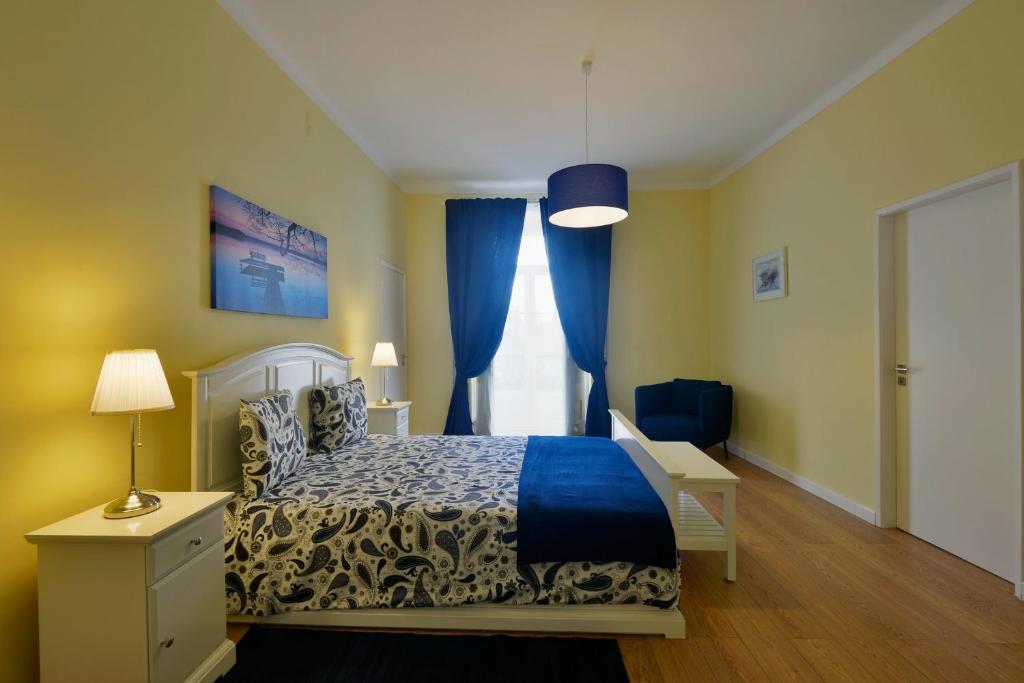 a bedroom with a bed and a window with blue curtains at FLH Bairro Alto - Chiado Spacious Flat in Lisbon