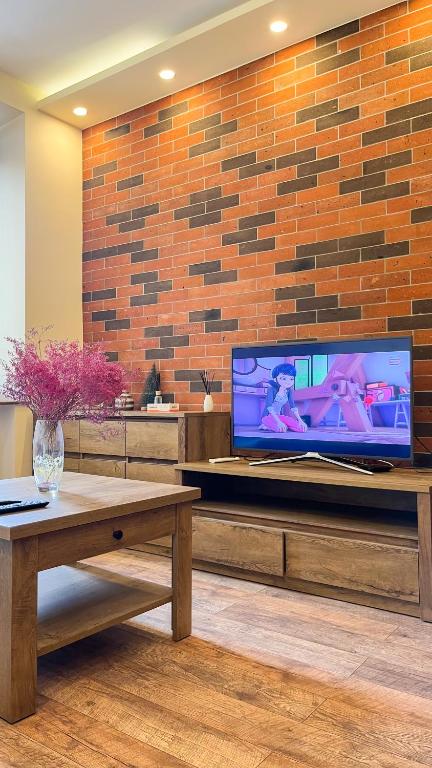 a living room with a large tv on a brick wall at Новая квартира у Площади in Yerevan
