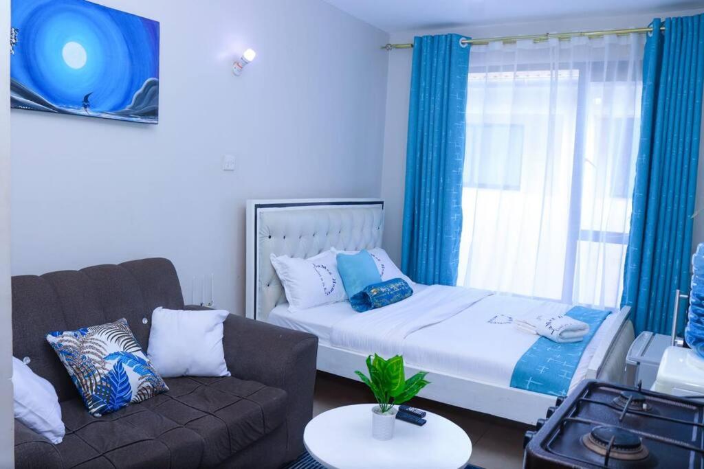 a living room with a bed and a couch at LaMeg2 Furnished Studio with Pool - Kiambu Rd in Nairobi