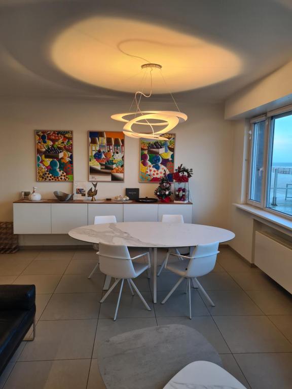 a kitchen with a white table and white chairs at frontaal gelijkvloers seaview 80m² 2 slp in Ostend