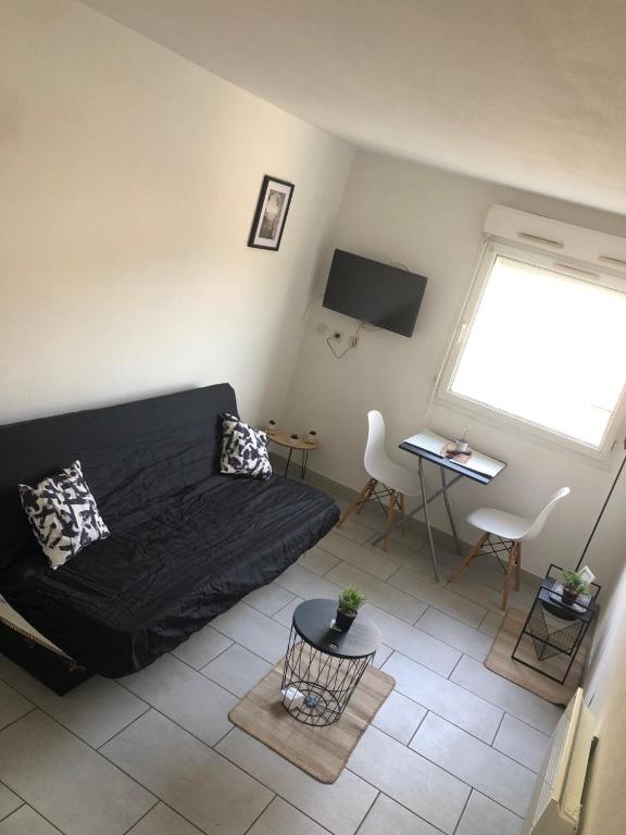 - un salon avec un canapé noir et une fenêtre dans l'établissement Studio quartier du port Nice, à Nice