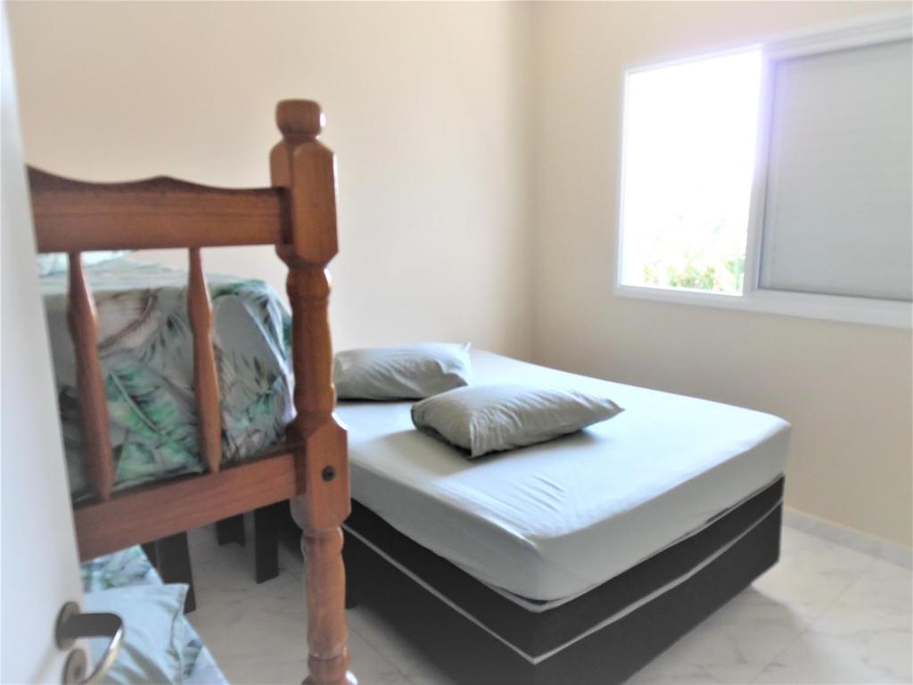 um quarto com uma cama e uma janela em Apto Aluguel na Temporada Pé na Areia Peruíbe SP em Peruíbe