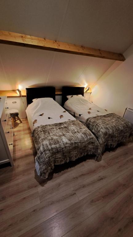 two beds in a room with wooden floors at Bike & Brake Fast Makkinga in Makkinga