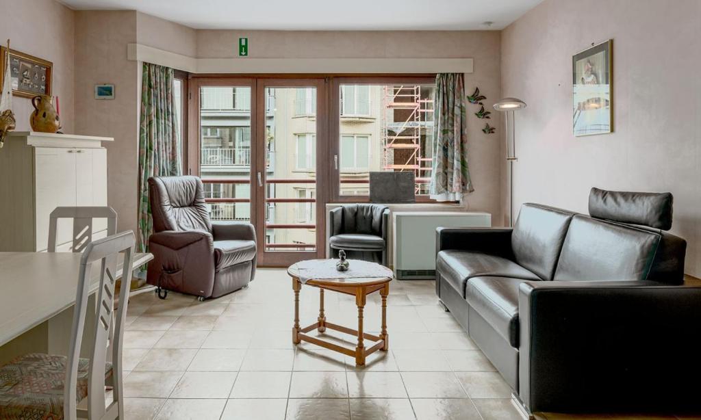 uma sala de estar com um sofá, cadeiras e uma mesa em Korre 0302 em Koksijde