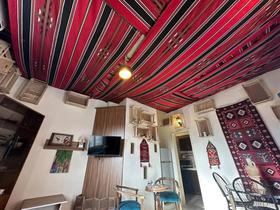 a room with red curtains and a table and chairs at Antica old apartment al-lwebdeh in Amman