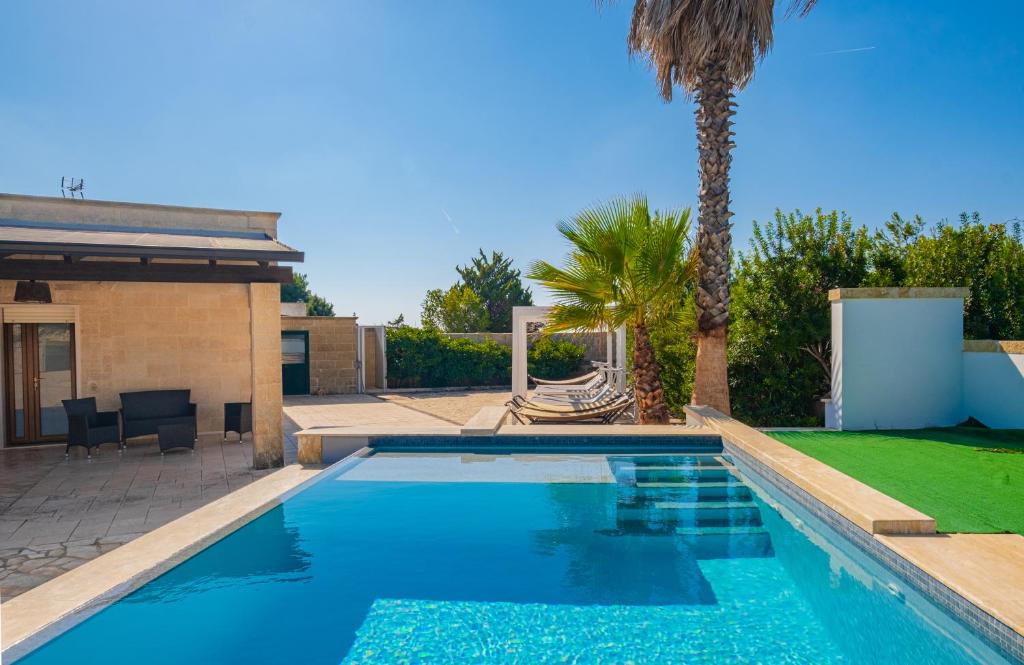 リド・マリーニにあるVilla Crigiada Luxury Poolの家の隣のヤシの木があるスイミングプール