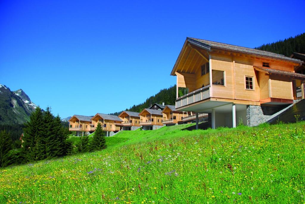 eine Reihe von Häusern auf einem Hügel mit einem grünen Feld in der Unterkunft Feriendorf Walserland in Damüls