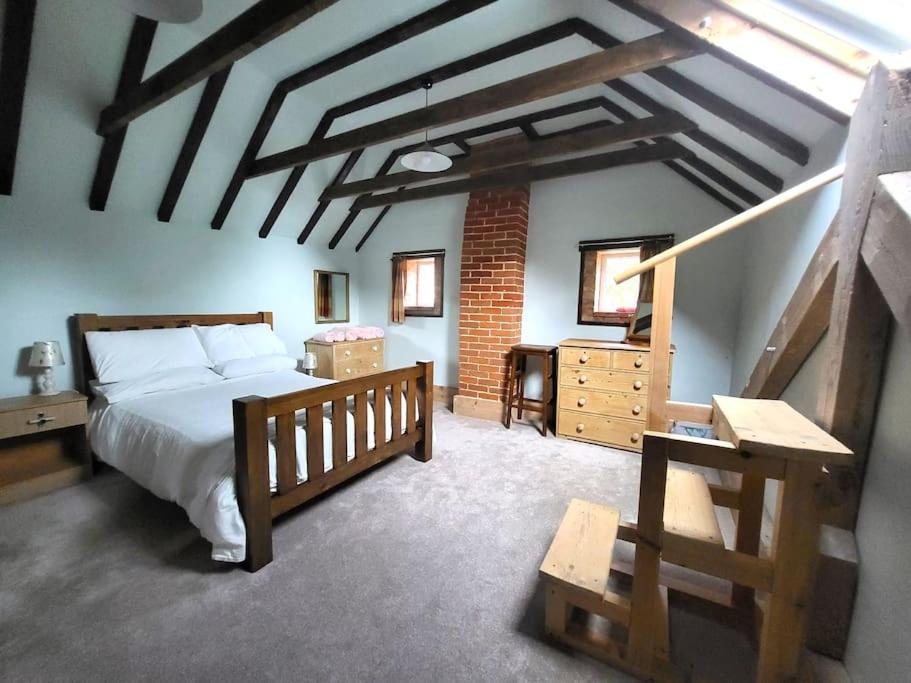 a bedroom with a large bed and a staircase at The Old Dairy in rural sea side location in Norwich