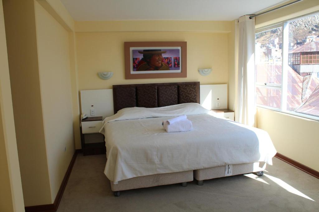 a bedroom with a bed with a towel on it at Kaaro Hotel El Buho in Puno