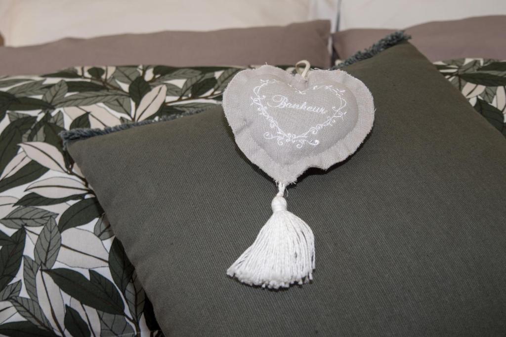 a heart shaped pillow with a tassel on a bed at Gite Oliveira&#39;s in Ury