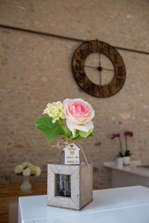 a flower in a vase in a wooden box with a clock at Gite Oliveira&#39;s in Ury