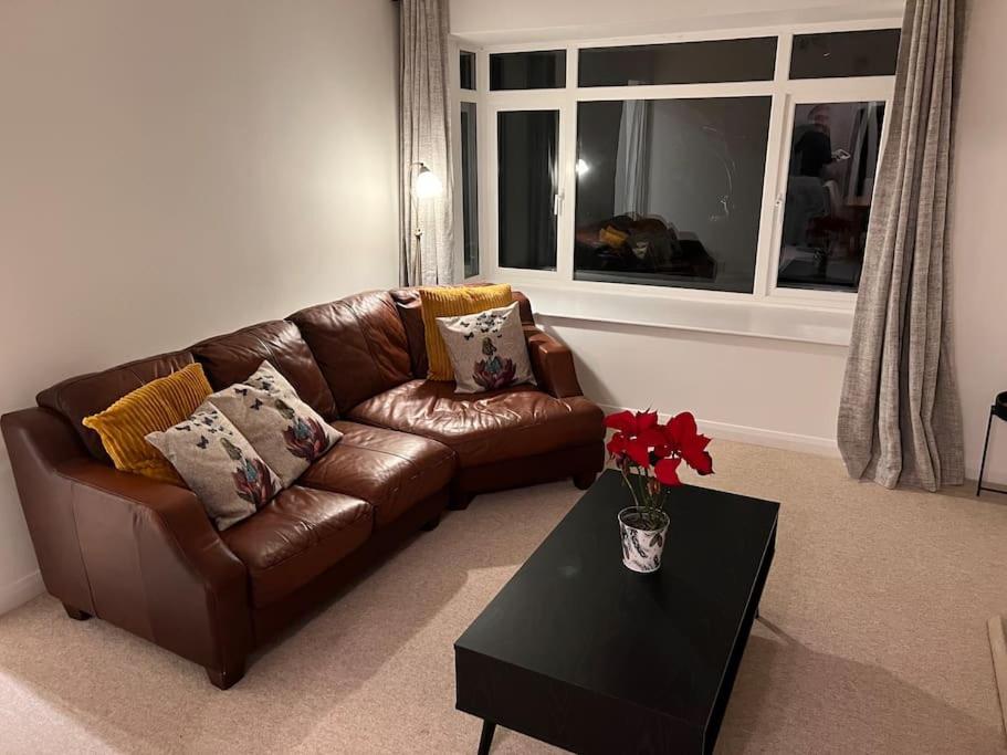 a brown leather couch in a living room with a table at Beautiful 1 bed bungalow in Ryde