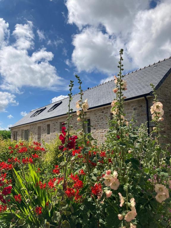 um jardim com flores em frente a um edifício em La longère de Poulrinou em Bohars