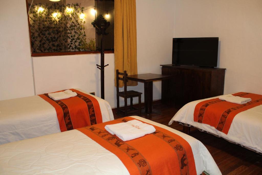 a hotel room with two beds and a flat screen tv at KAARO HOUSE CUSCO in Cusco
