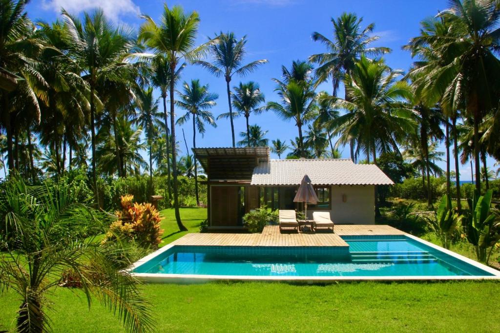 a villa with a swimming pool and palm trees at Hygge Residence - Barra Grande - Península de Maraú in Marau