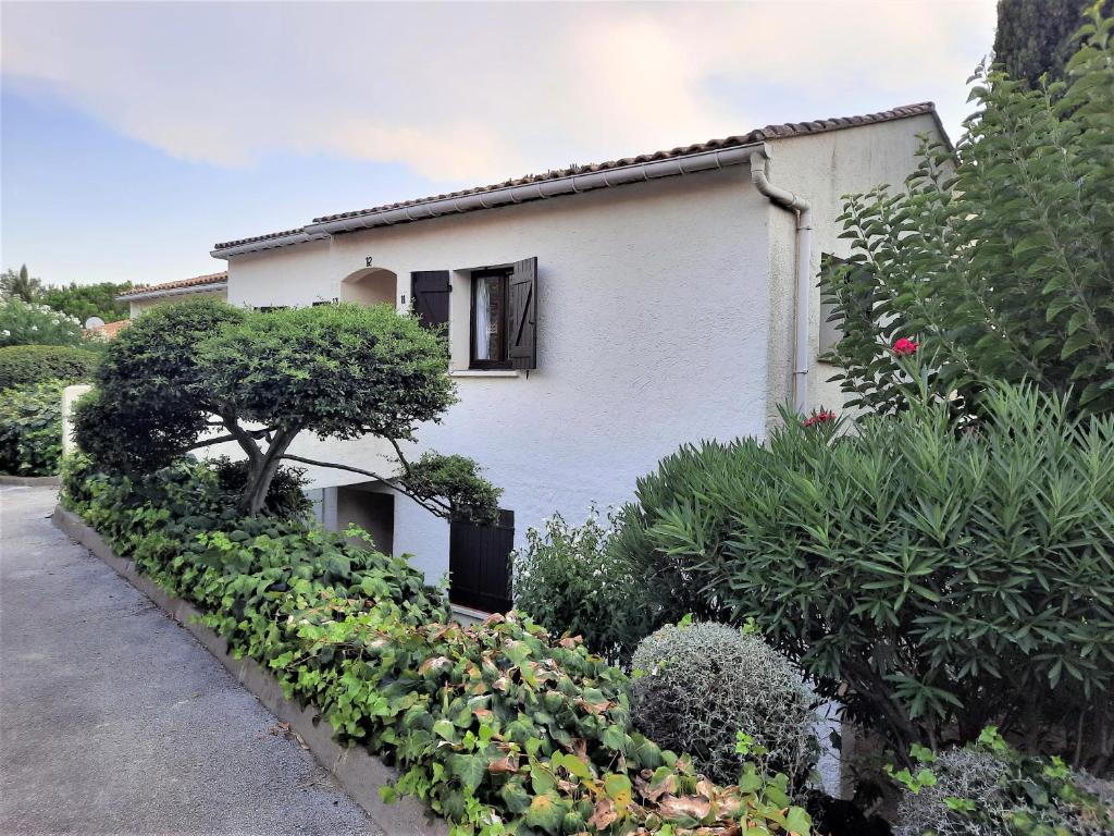 une maison blanche avec un jardin en face dans l'établissement Cavalaire sur mer Appartement T3-160 m plage - 800 m Centre-ville. Park, à Cavalaire-sur-Mer