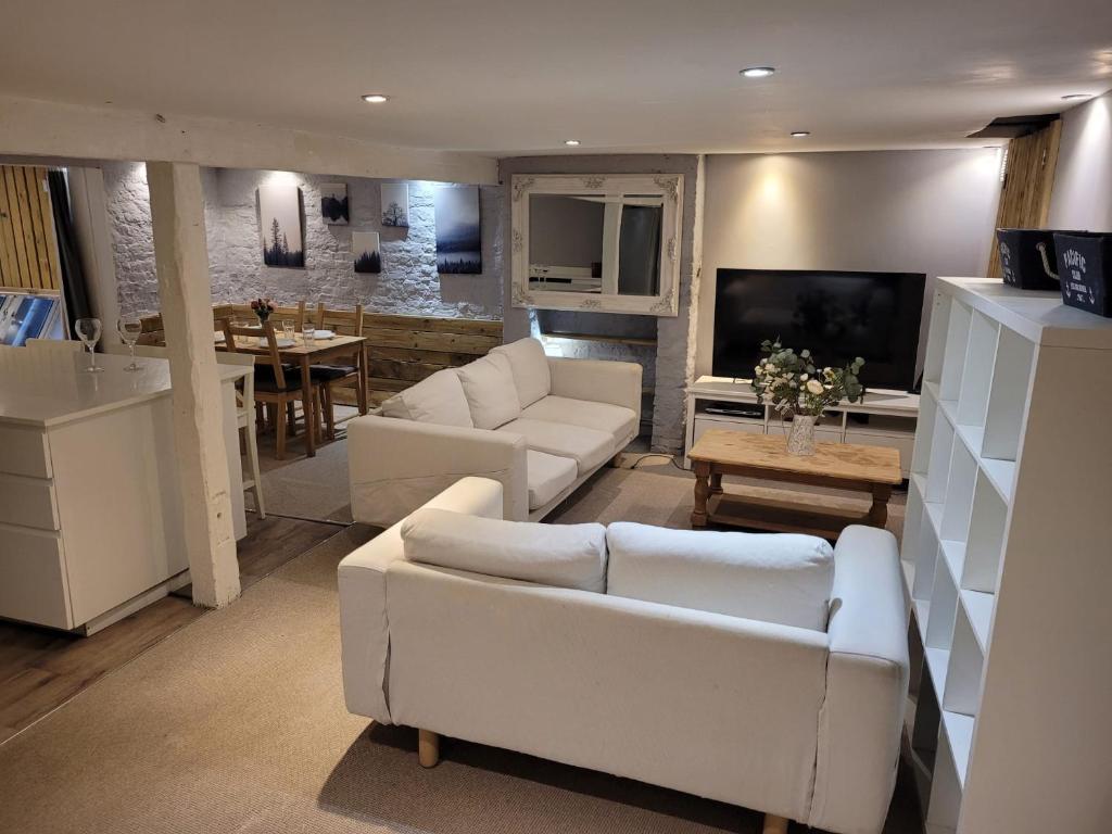 a living room with two white couches and a kitchen at Beach Walk Sandgate in Sandgate