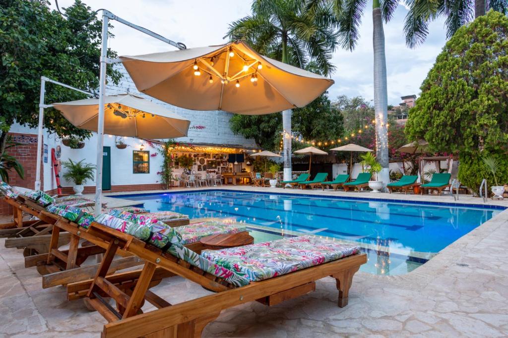 a swimming pool with chairs and umbrellas next to a pool at Entre Palmas Casa Hotel in Santa Fe de Antioquia