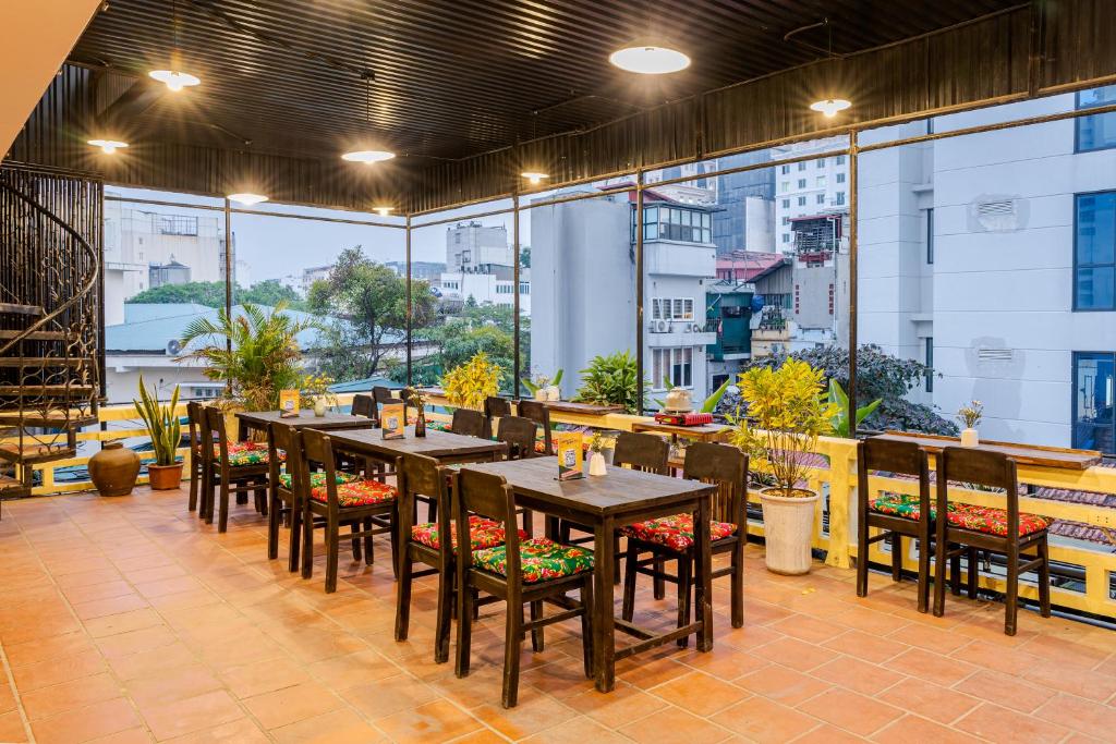 un ristorante con tavoli, sedie e ampie finestre di Hanoi Retro 80S Homestay a Hanoi