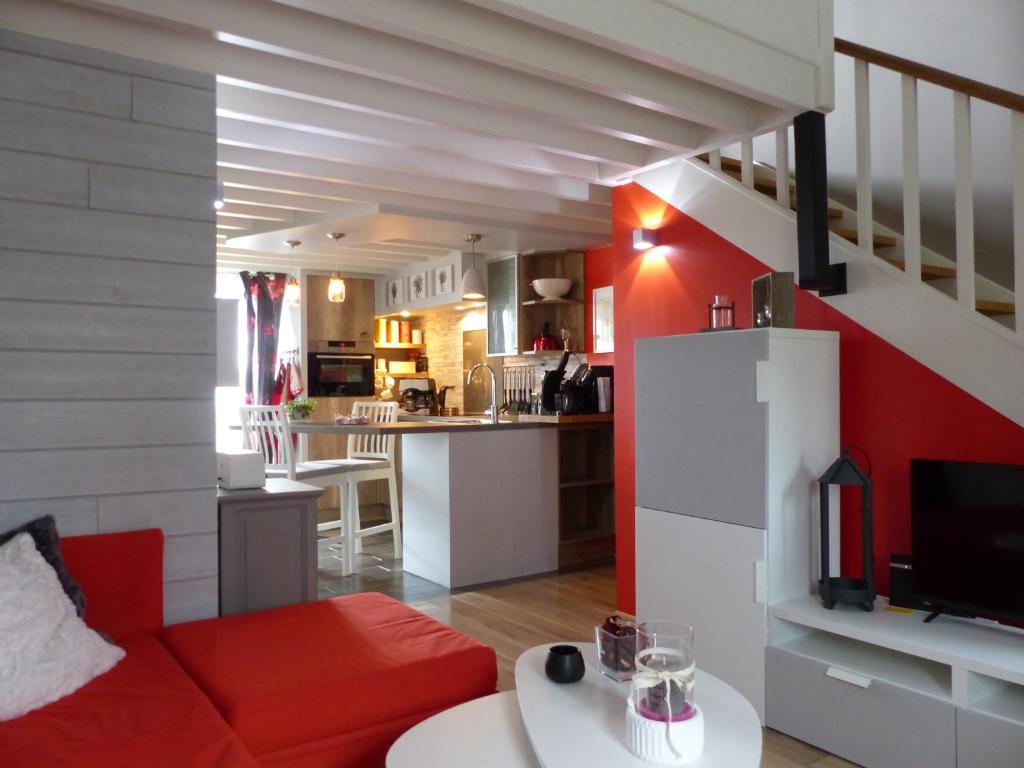 a living room with a red couch and a kitchen at Au Ptit Coquelicot in Houyet