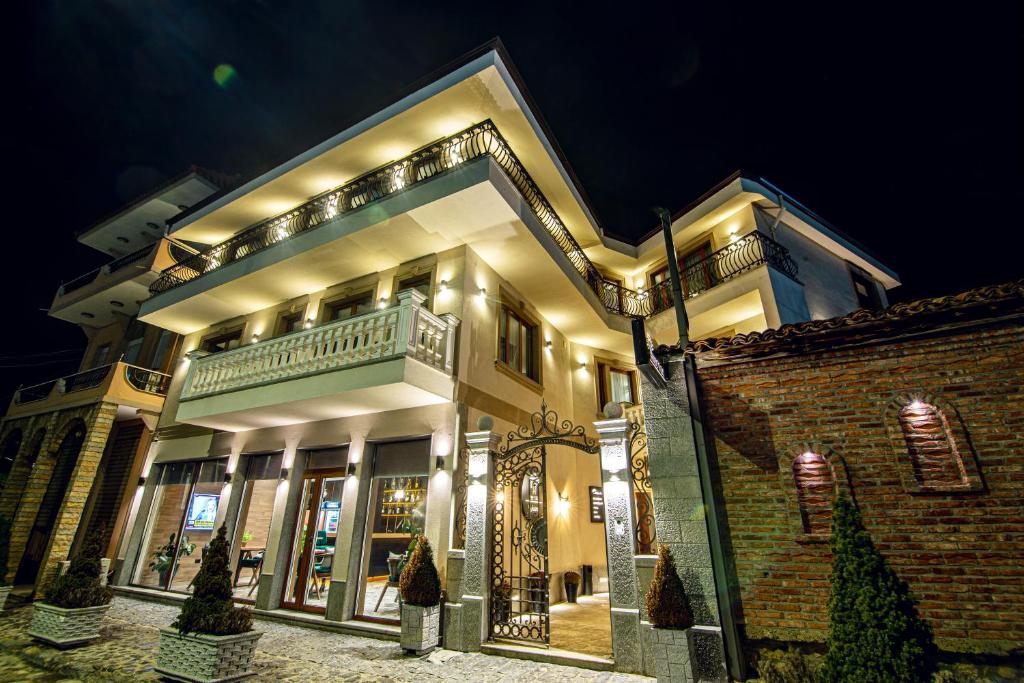 a building at night with a woman standing in front of it at Tree Hotel in Korçë