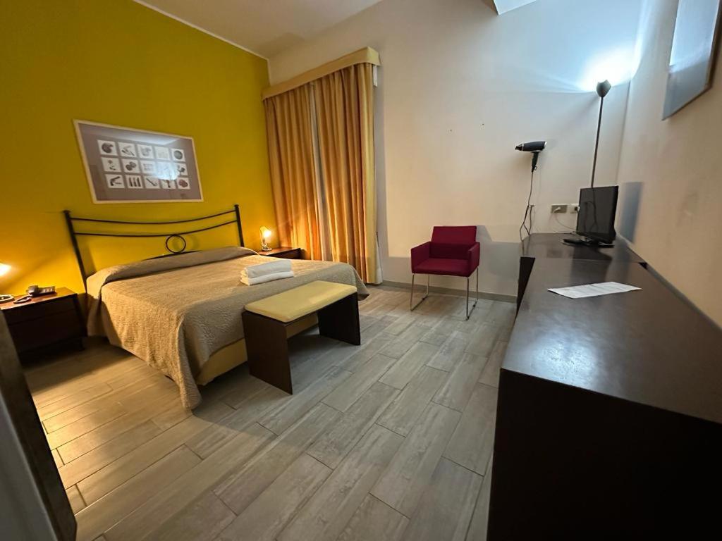 ルバーノにあるホテル レ カランドレのベッドと赤い椅子が備わるホテルルームです。