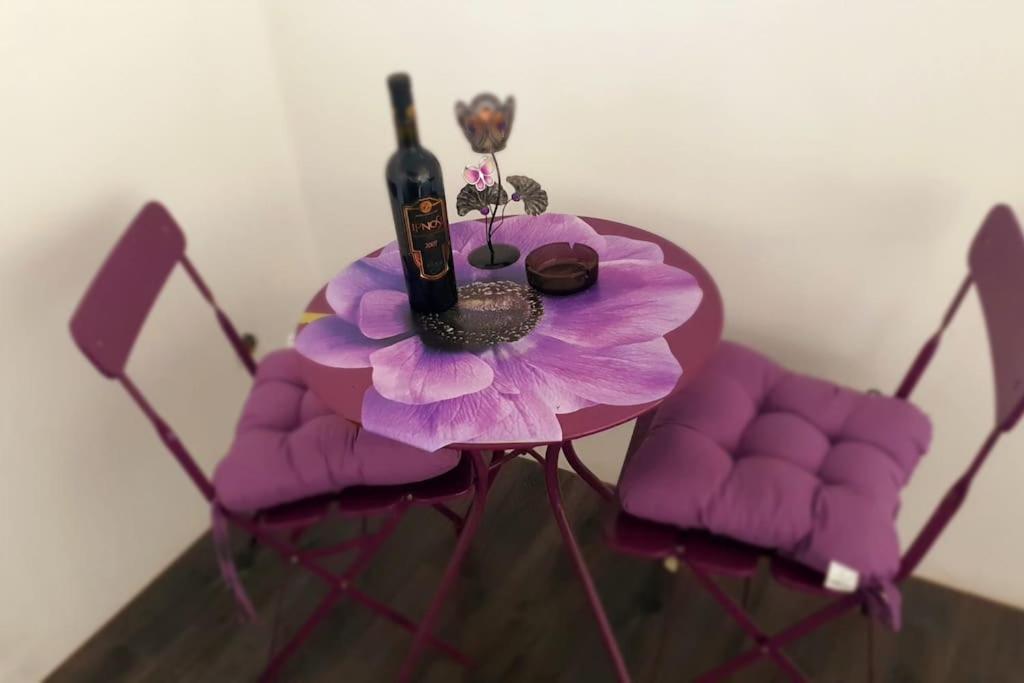 una mesa púrpura con una botella de vino y una flor en Елегантен градски апартамент с обширна тераса, en Pernik