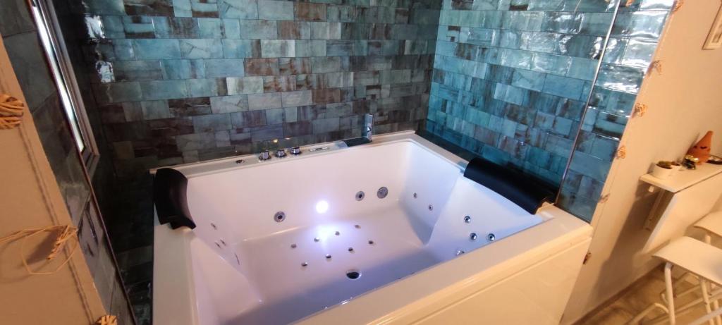 y baño con bañera y pared de azulejos. en Latorre jacuzzi jerez, en Jerez de la Frontera