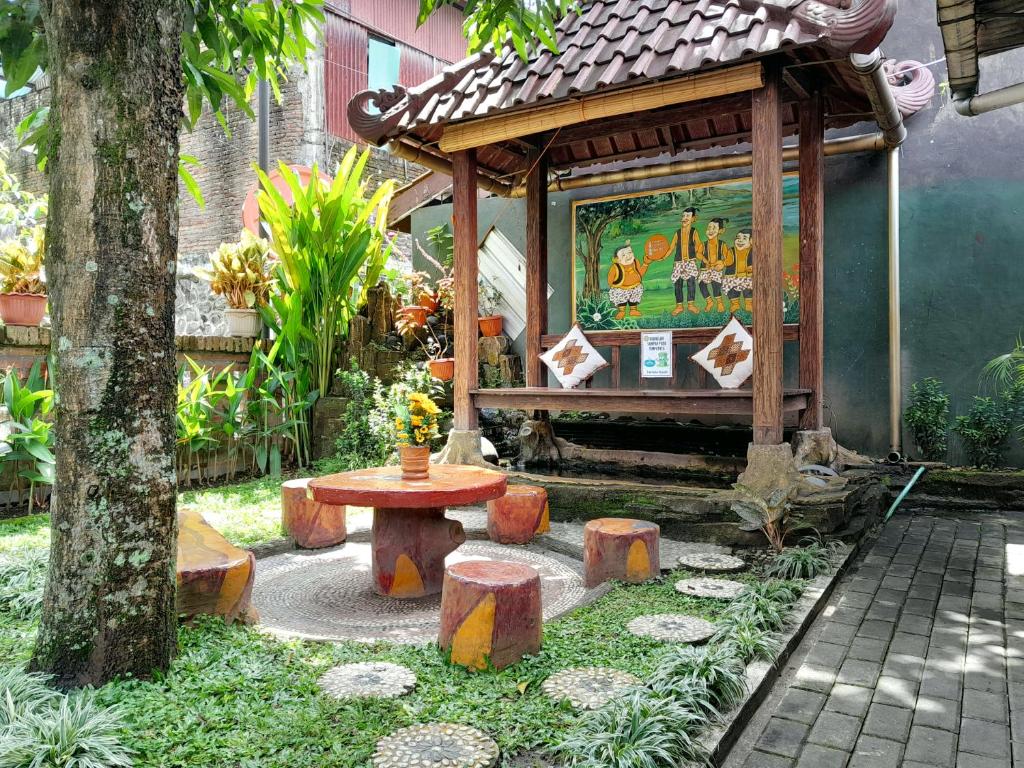 einen Garten mit einer Bank, einem Tisch und einem Baum in der Unterkunft Ngampilan Backpacker Hostel in Yogyakarta