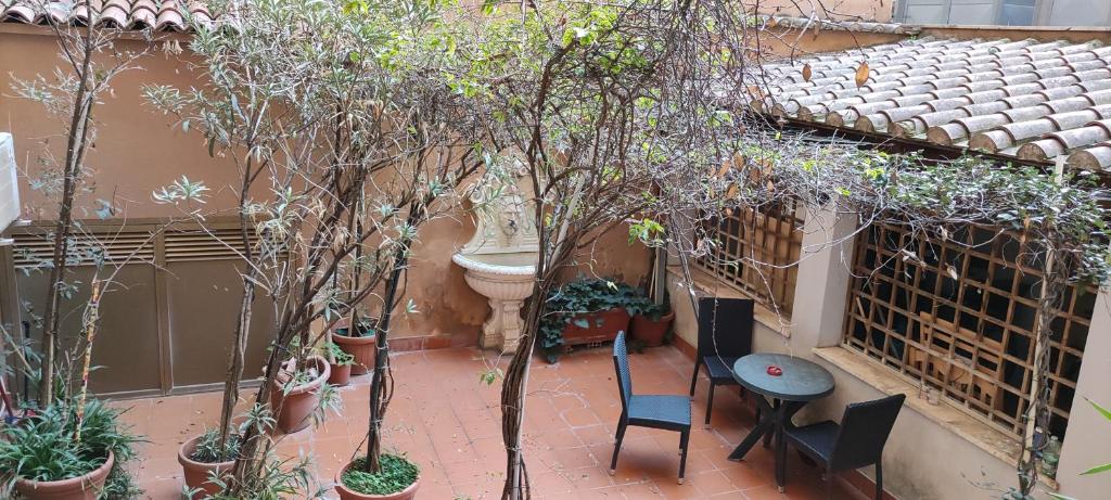 un patio con tavolo, sedie e alberi di Hotel Montreal Uno a Roma