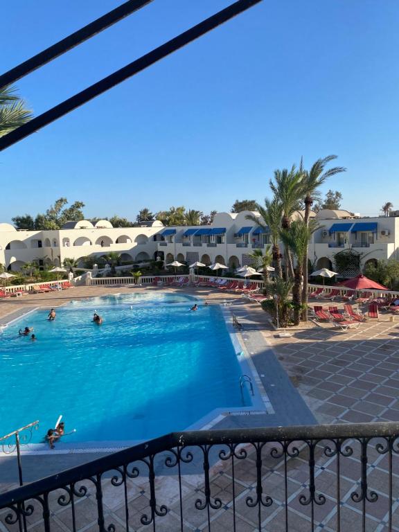 een balkon met uitzicht op het zwembad van een resort bij Le Petit Palais Djerba & Spa in Houmt Souk