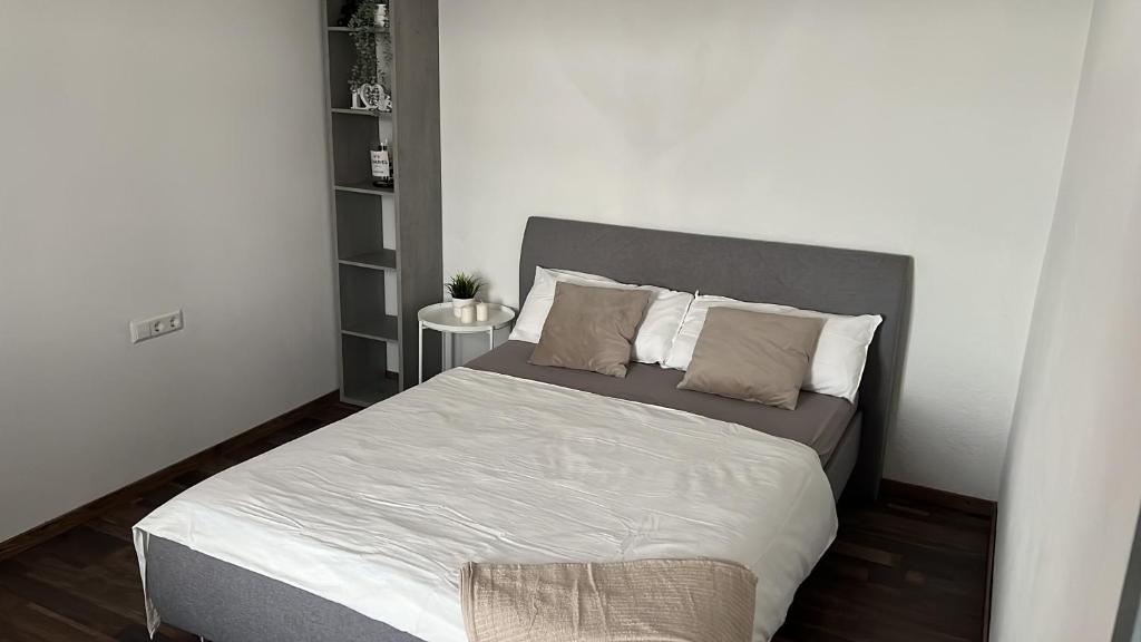um quarto com uma cama grande com lençóis brancos e almofadas em Sivas Ferienwohnung em Ravensburg