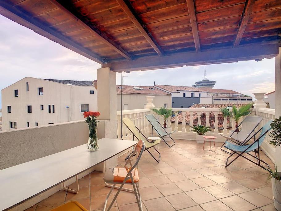 a balcony with chairs and a table on a building at Rare maison à 50m de la plage. Grande terrasse vue mer. in Palavas-les-Flots