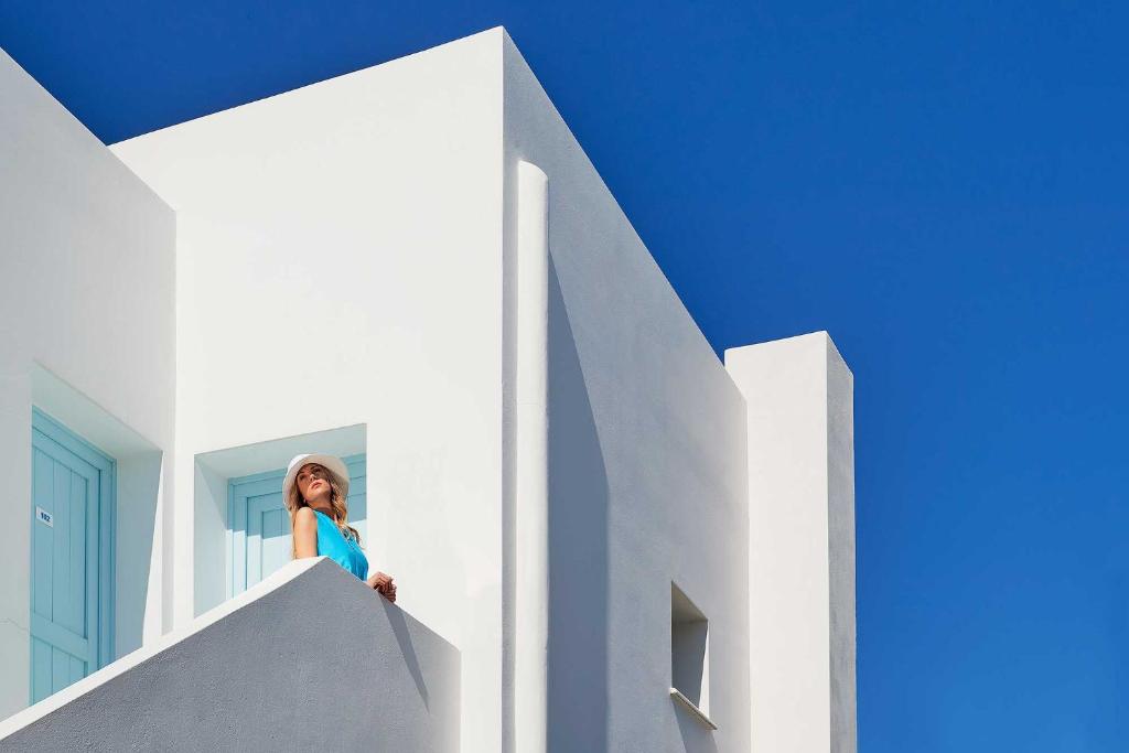 a woman standing on the side of a white building at Perigiali in Skiros