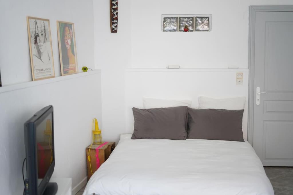 a bedroom with a white bed and a tv at Rare maison à 50m de la plage. Grande terrasse vue mer. in Palavas-les-Flots