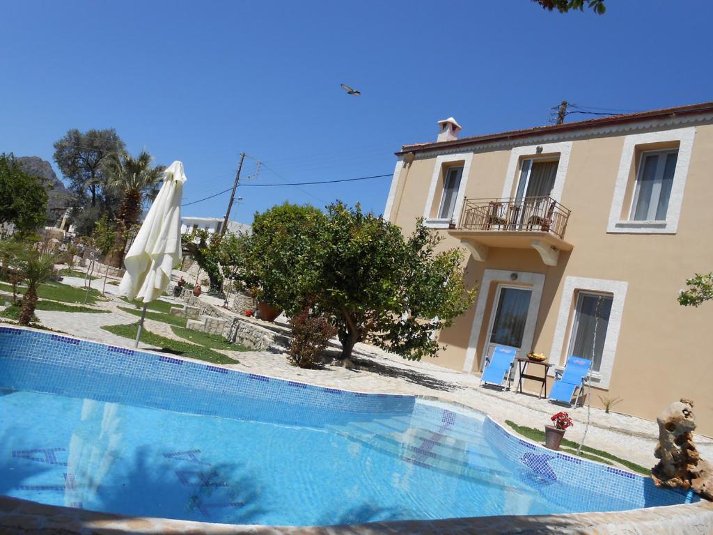 a swimming pool in front of a house with an umbrella at Villa Petra with heated pool in Kalochorafitis
