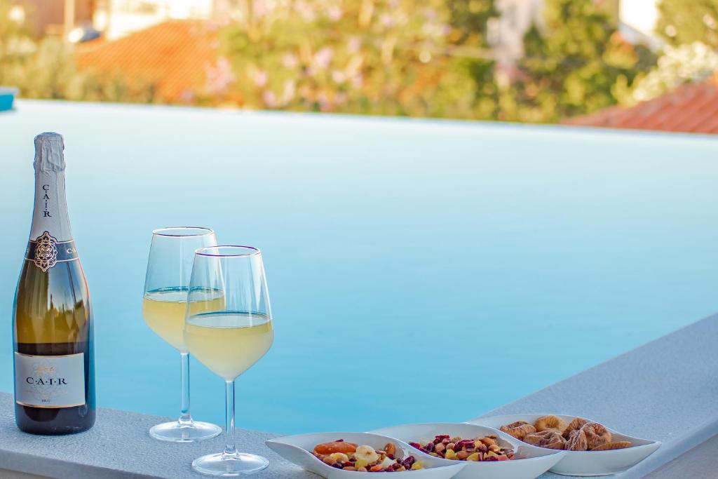 una botella de vino blanco y dos copas de comida en Georgianna's suite with private pool , 'greysuite', en Kómboi