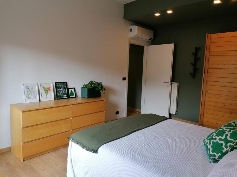 1 dormitorio con cama blanca y tocador de madera en Arona 03 centralissimo ampio bilocale con garage, en Arona
